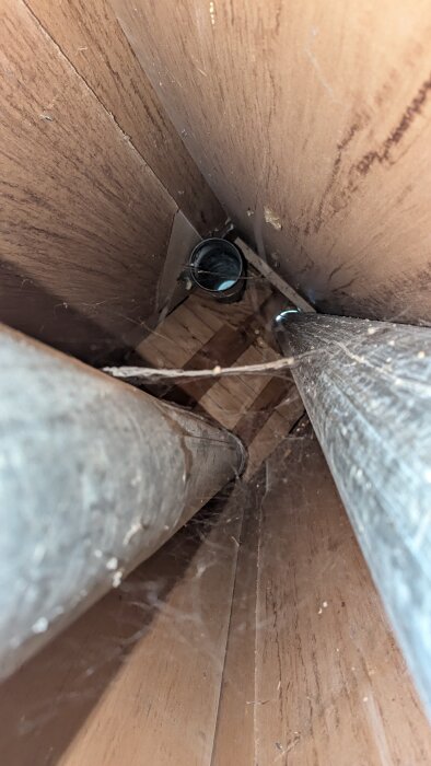 Öppnad ventilations trumma med två rör och spindelväv inuti, ett rör ej anslutet. Möjligt plats för mekanisk fläkt.