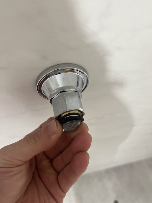 Gängor på ett vatettefäste med kromad yta, hålls i handen.