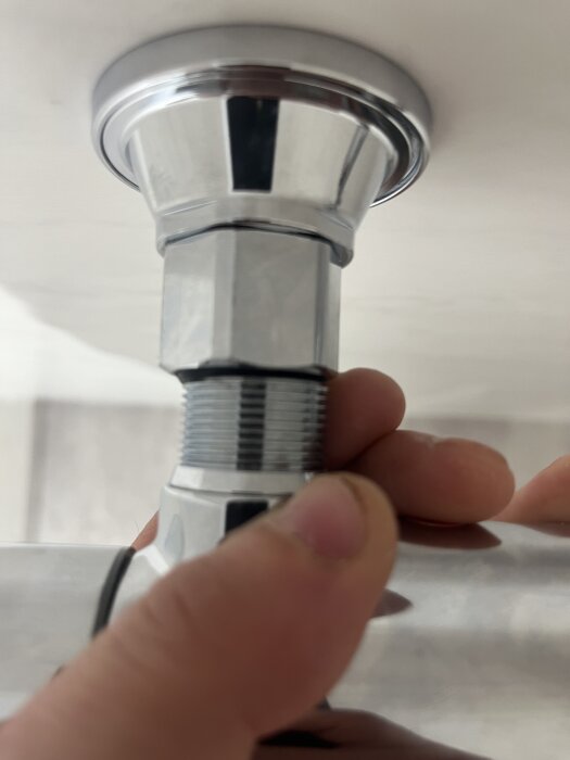 Duschblandare monteras mot vägg, händer försöker fästa den på gängorna; problem med passform och solens medföljande delar.