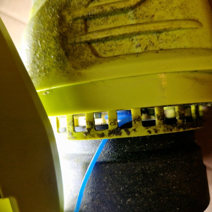 Närbild av en Ryobi OLT1832 där trimmertråden har fastnat i spolen. Tråden är blå och syns delvis genom spolskenorna.