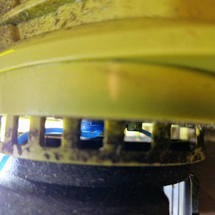 Närbild av trimmerhuvud på en Ryobi OLT1832 där blå tråd har fastnat i spolhöljet.