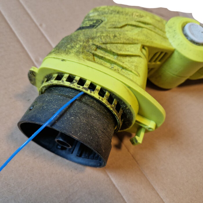 Närbild av en Ryobi OLT1832 där tråden har fastnat i spolen på en ovanlig plats, med kapskyddet avlägsnat.