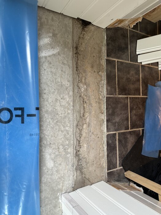 Ojämn betongyta där ytterdörren tidigare satt, med brädlappar och plastark synliga runt om.