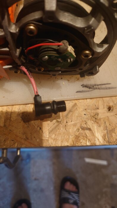 En gnistmodul med kablar till en Paslode Impulse IM 350/90 CT, placerad på en arbetsbänk av träfaner.