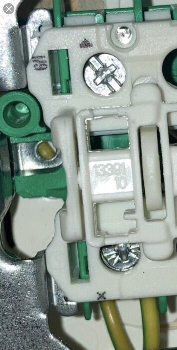 Trappströmbrytare med synlig jordtråd på X-plint i närbild, 6/1 specifikation.