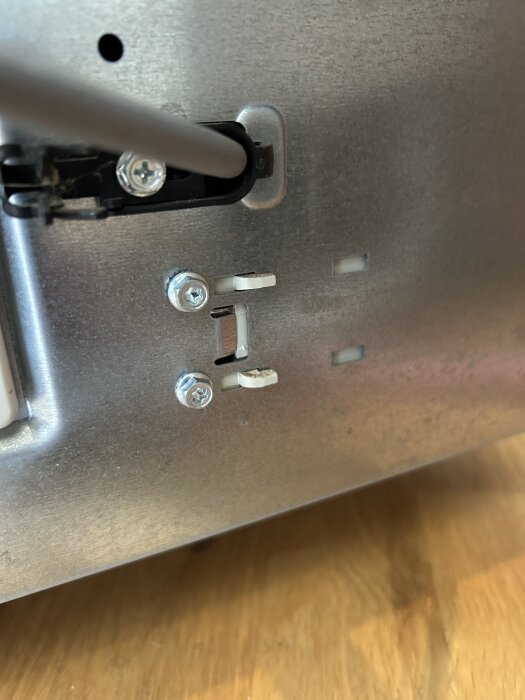 Baksidan av en Whirlpool-diskmaskin med monterade skruvar och tomma skruvhål synliga.