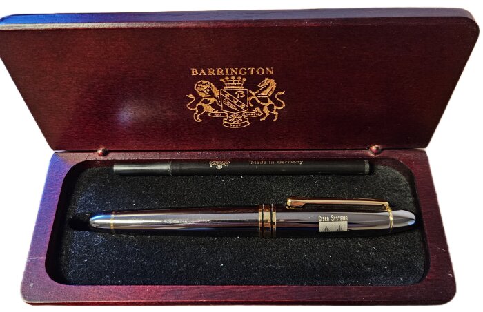Penna märkt "Cisco Systems" i en öppen trälåda med text "Barrington", fodralet "Made in Germany".