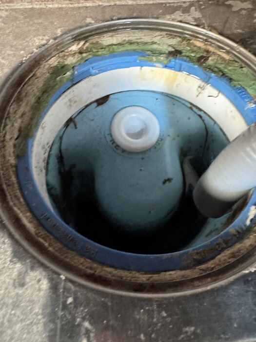 Avloppshål med en nyinstallerad propp förhindrar avloppslukt, omgiven av gammalt förseglingsmaterial.