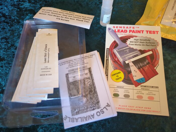 Testkit för bly i färg med testremsor, instruktioner och förpackning som visar "SENSAFE LEAD PAINT TEST" och en pensel avbildad.