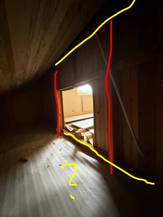 Bild av kattvind med träramar; vertikala reglar markerade med rött, horisontella med gult. Ljusinsläpp från fönster, golv täckt av byggmaterial.