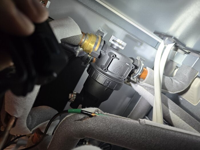 Innerdelen av en modern Panasonic luftvärmepump med rör och filter synligt, utan kranar på sidorna.