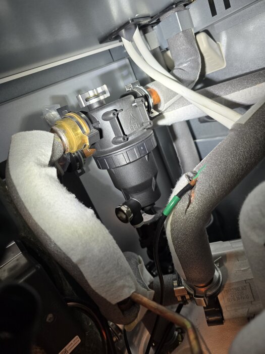 Insidan av luftvärmepump visar rör och filter utan kranar på sidorna.