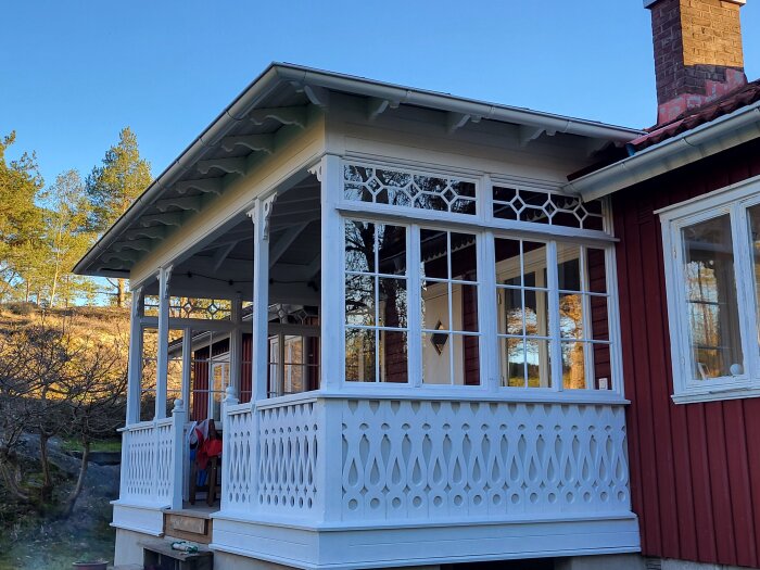 En nyrenoverad veranda med vita detaljer på ett falurött hus. Fönstren är nyligen monterade och trappen byggd.