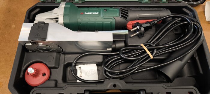 Verktygssats från Parkside med elektriskt verktyg, kabel, fästelement och manual i en öppen väska på ett bord.