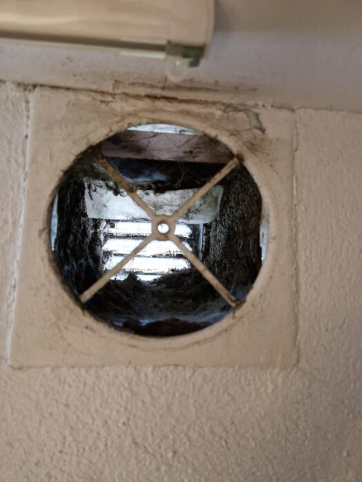 Ventilationsöppning i källarvägg med fyrkantigt galler och smutsackumulering, diskussion om modernisering och förbättring av luftkvalitet i tråd.