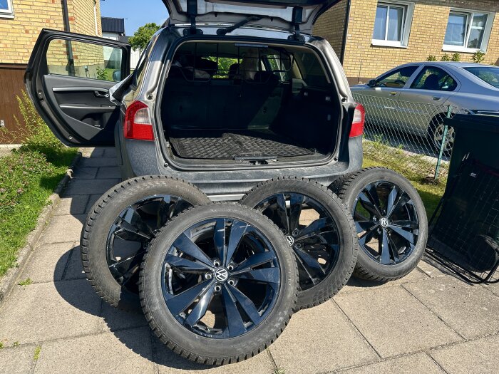 Fyra Volkswagen-hjul står uppställda vid bagageutrymmet på en bil, redo för rengöring och underhåll i ett garaget.