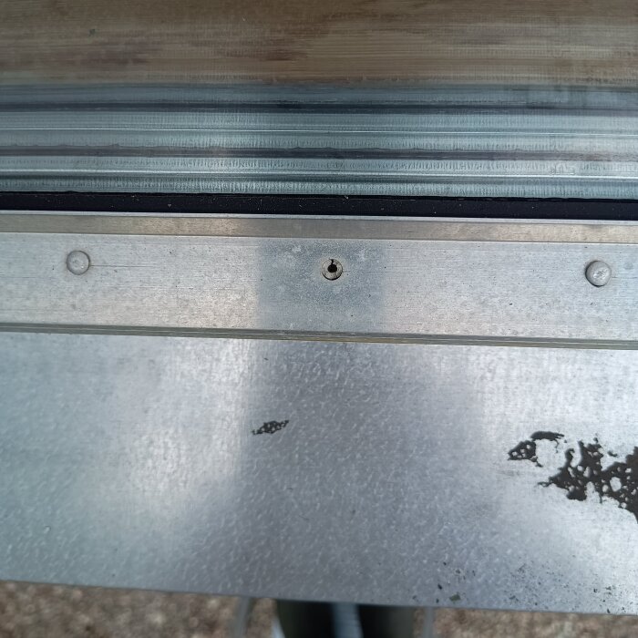 Treglasfönster med metallbleck, hål i mitten och tecken på slitage eller skada.