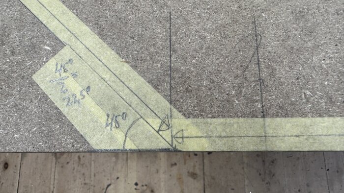 MDF-skiva med ritade linjer och vinklar, tejp markerar hörn och vinklar på 45° och 22,5°, del av plan för spelbordsprojekt.
