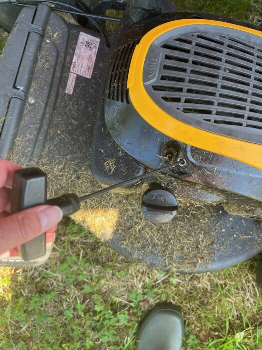 Gräsklippare av märket Stiga Combi 553 S med fastnat startsnöre, en hand håller i handtaget över gräs.