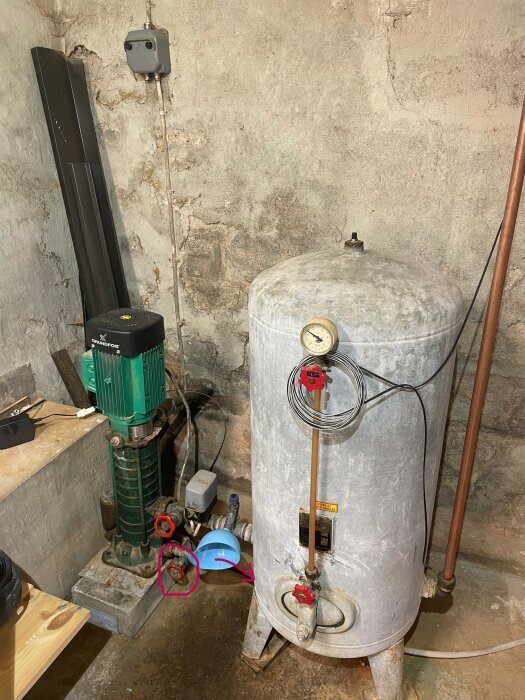 Pump och trycktank i ett källarutrymme, typiska komponenter för en egen brunn på fastigheten.
