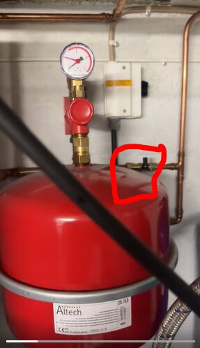 Expansionskärl för värmesystem med röd påfyllningsventil inringad, omgiven av svart Armaflex-isolering och kopparrör.