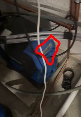 Blå pump med synlig typskylt, omgiven av rör och elkablar i ett utrymme.