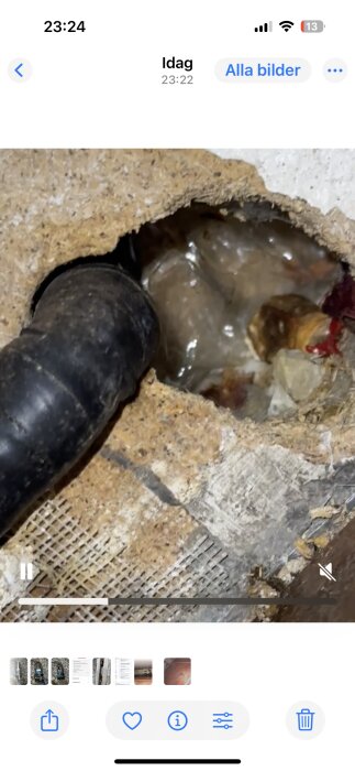 Skadad köksvägg med ett rör och vattenskada synlig i isoleringen bakom väggen.