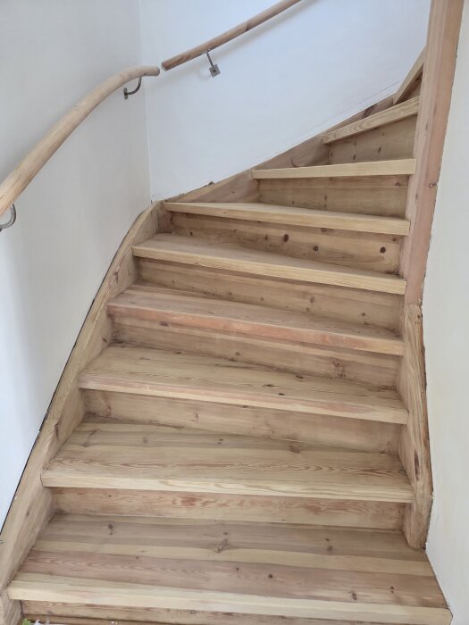 Trätrappa inomhus med grön-grå-gul nyans efter lutbehandling; ljusa väggar och trähandledare syns.