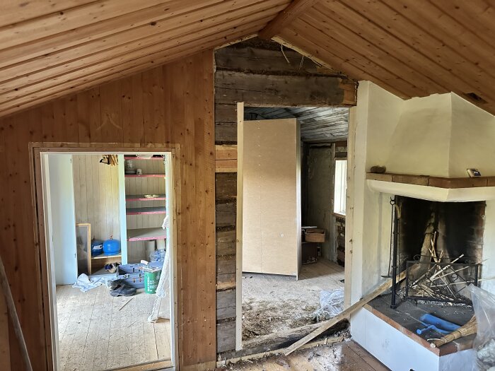 Renovering av timmerhus med synlig timmervägg. Ny dörröppning mellan kök och allrum, gammal öppning ska reglats upp. Eldstad syns till höger.