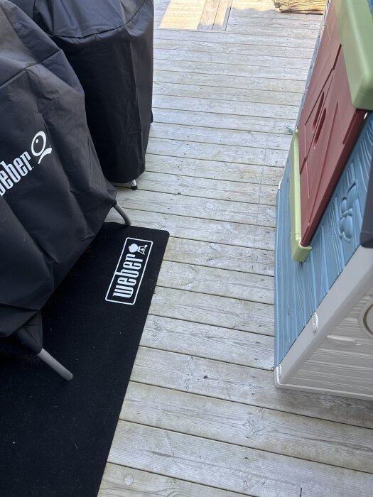 Trätrall på altan med grillskydd och lekstuga, där kablar ska dras mellan reglar närmast husväggen.