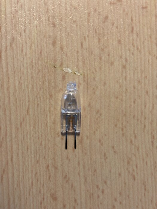 Liten tvåbent glödlampa liggande på träyta.