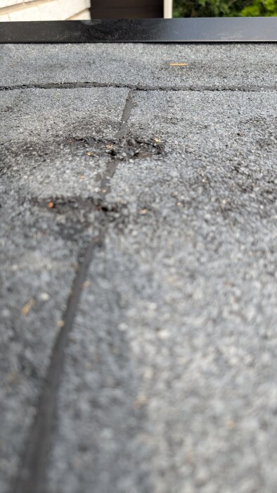 Skadad ytpapp på balkonggolv med repor och ojämnheter, nära plåtkant, visar möjlighet till kosmetisk skada utan genomgående hål.