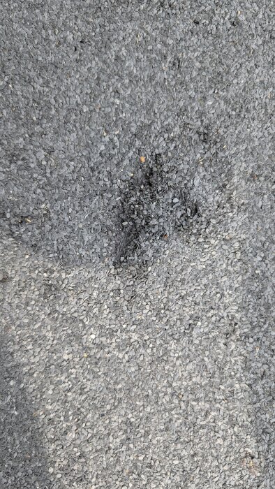 Skadad ytpapp på balkonggolv, med synlig ytlig skada utan hål. Området verkar slitet men inte trasigt rakt igenom.