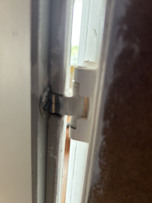 Gångjärn från 60-/70-tal på en garderobsdörr, delvis utslitet.