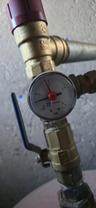 Tryckmätare på expansionskärl med en pekare som visar cirka 1,8 bar, sitter på en kopparledning med blå ventil.