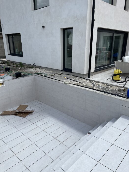 Kaklad pool under konstruktion bredvid ett modernt hus.