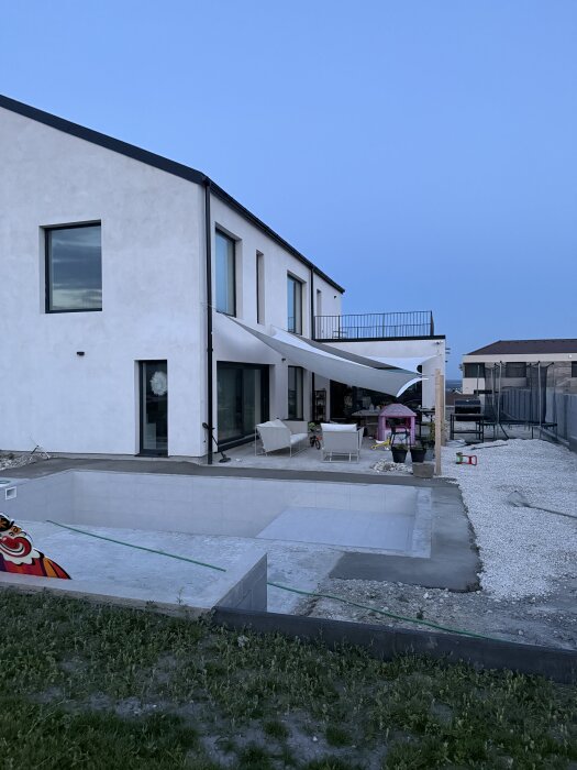 Modern villa med en pool under konstruktion och markarbete runt om.