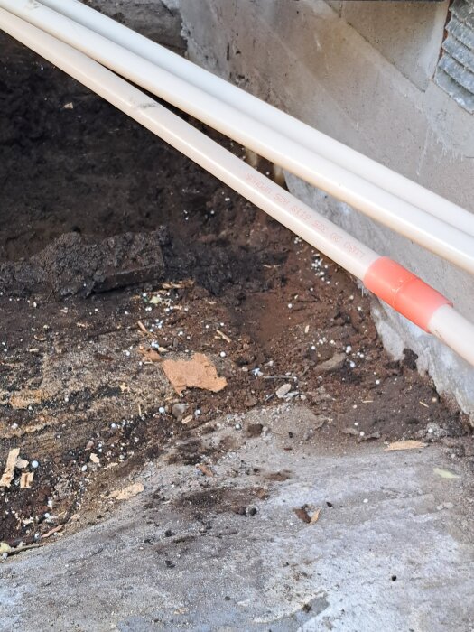 Rör och jord vid betongvägg i byggprojekt.