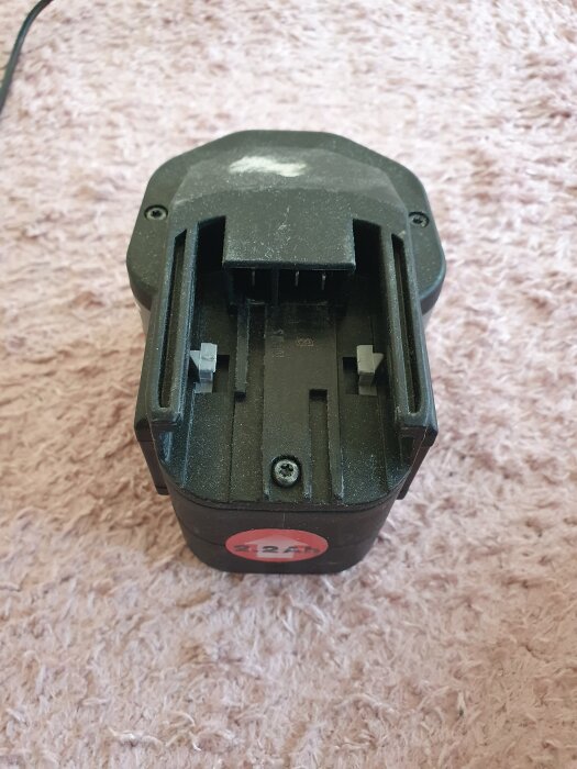 Batteri med fokus på polerna längst till vänster, liggande på rosa matta.