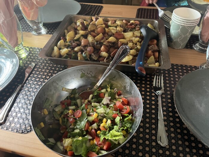 Pytt i panna i ugnsform serverad med sallad i skål, dukat på bord med bestick.