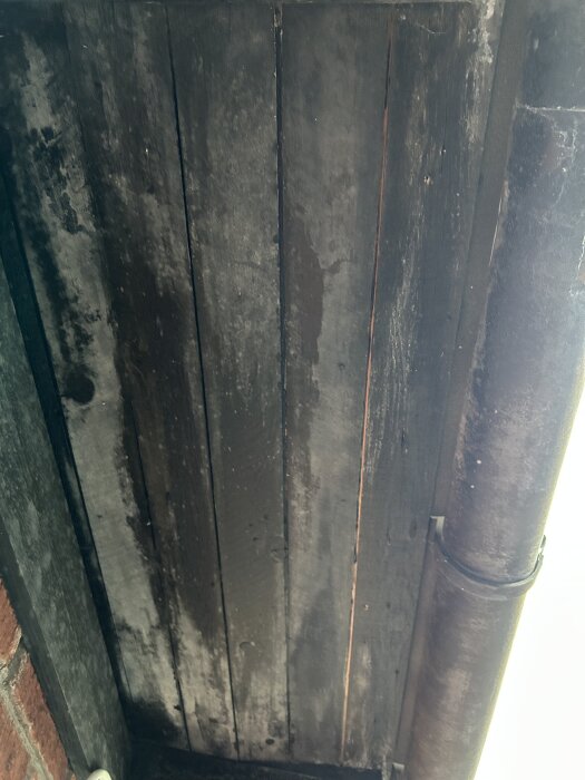 Sliten takfot med sprucken färg och rörledning, fotad rakt underifrån.