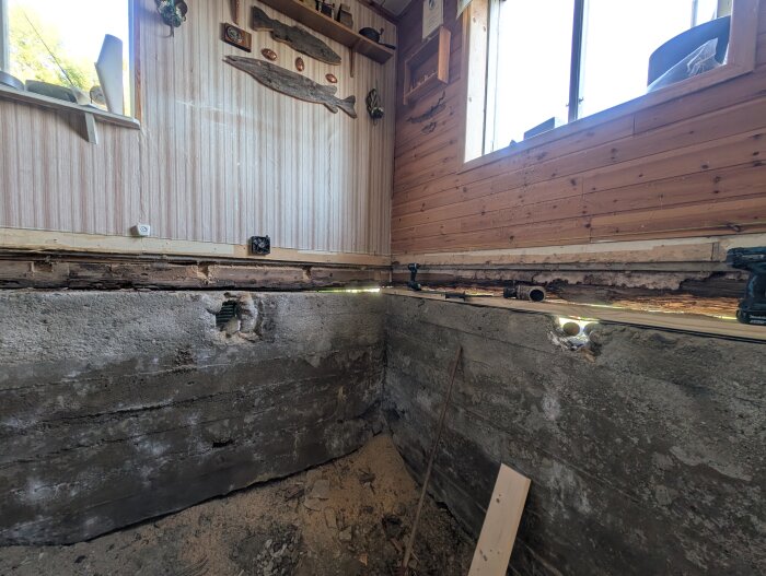 Grundmur och vägg i renoveringsprojekt, synlig träregel och verktyg på plats. Pejl av förankring till ny syll.