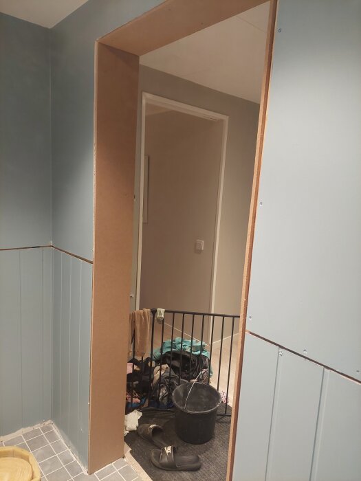 Gipsad fönstersmyg och rå MDF som dörrsmyg i en dörröppning, material och verktyg synliga i rummet.