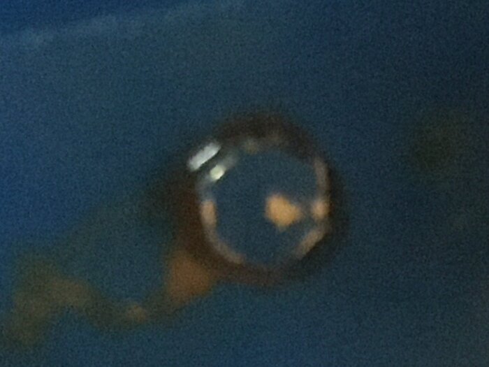 Närbild av en skruv på en blå yta i ett pumphus, möjligen kopplad till vattenpåfyllning eller en backventil.