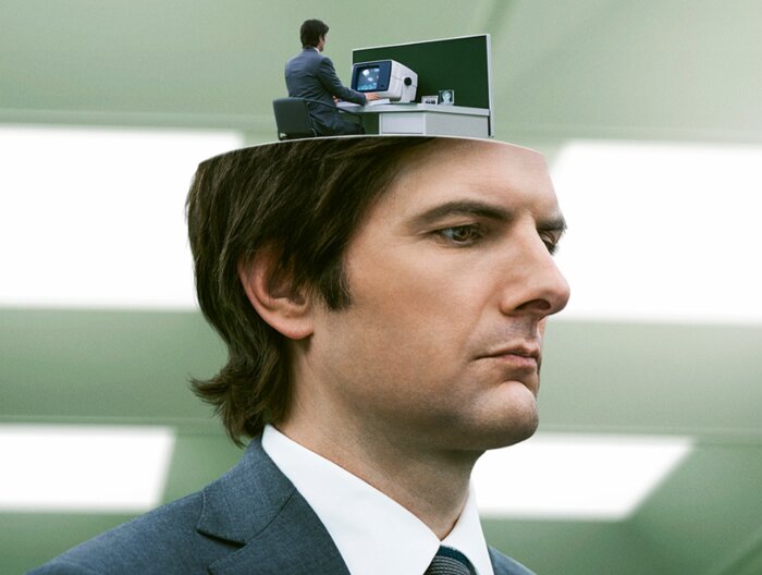 En man i kostym med en öppen hjärna där en annan man iakttar en datorskärm, symboliserar tankearbete och introspektion.