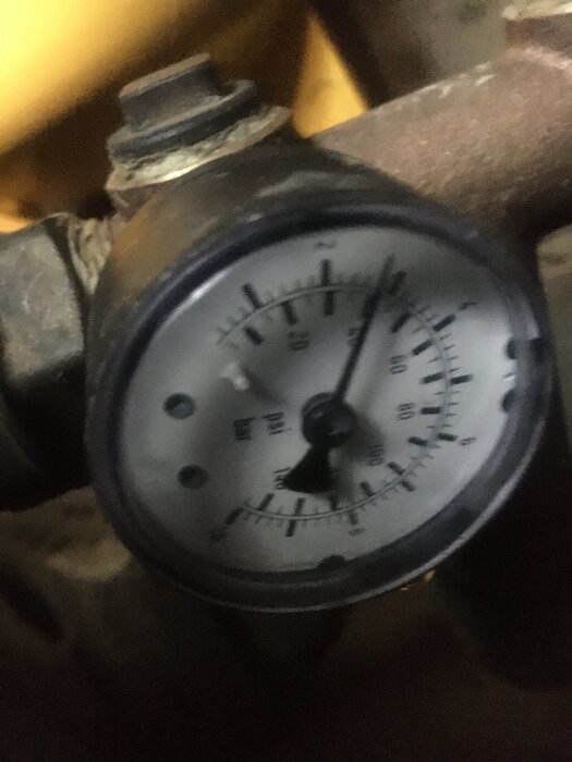 Tryckmätare med viss suddighet, visande trycknivån i en rörledning, relaterad till problem med vattenkran.