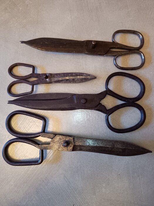 Fyra gamla saxar av metall från Eskilstuna, tillverkade av B O Libergs fabriksaktiebolag, placerade på ett bord.