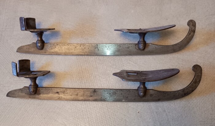 Två gamla metallskridskor från Rosenfors manufakturverk i Skogstorp, Eskilstuna, med krokig framdel och plats för montering på skosula.