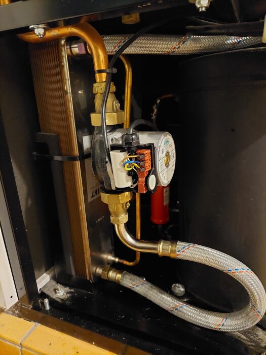 En installation med VVS-rör och ventil som visar en hemmagjord reparation med en cirkulationspump och anslutna ventiler.