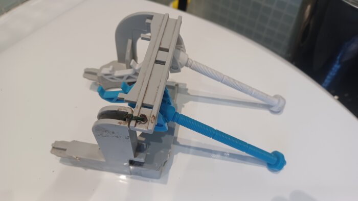 Okänd spolmekanism med blå och vita plastkomponenter, möjligtvis av polskt ursprung. Ligger på ett vitt underlag.